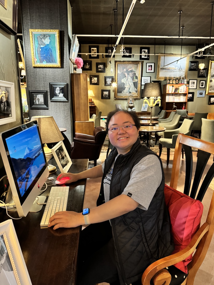 Vina Melody in front of an iMac, in a room full of retro photo frames.